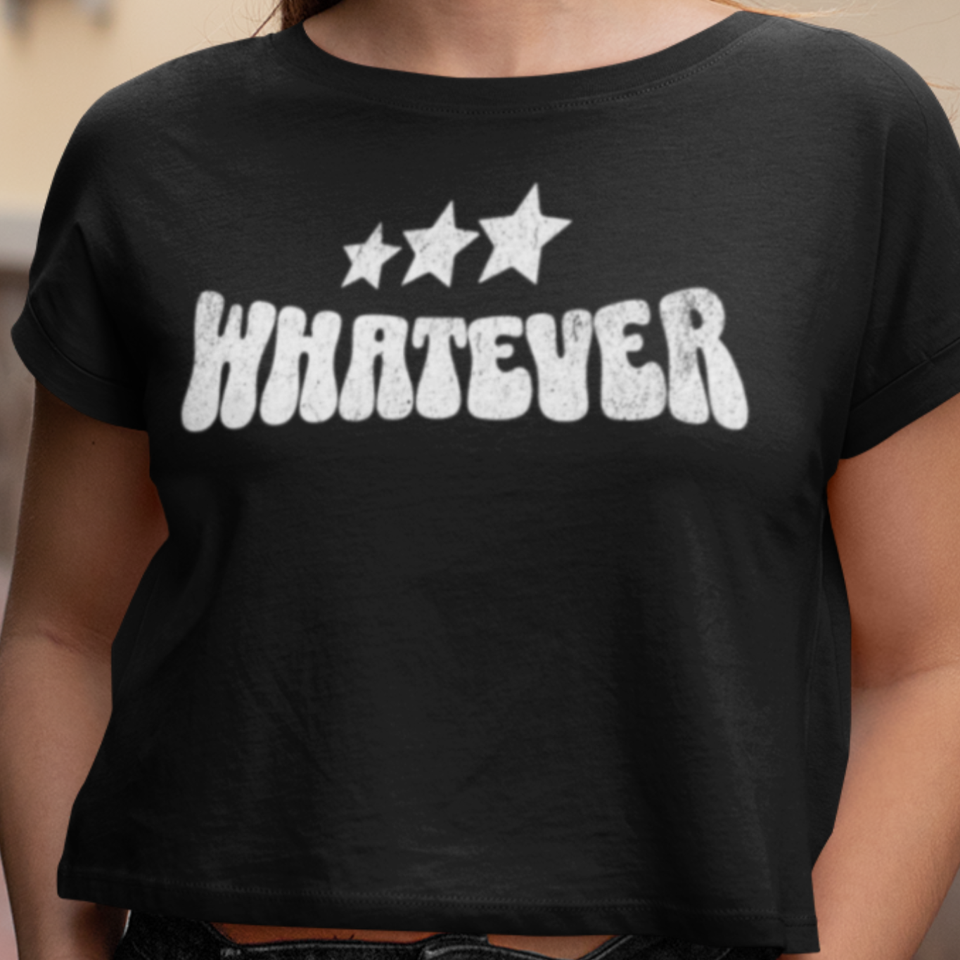 Person wearing a black t-shirt with 'WHATEVER' and star graphics.