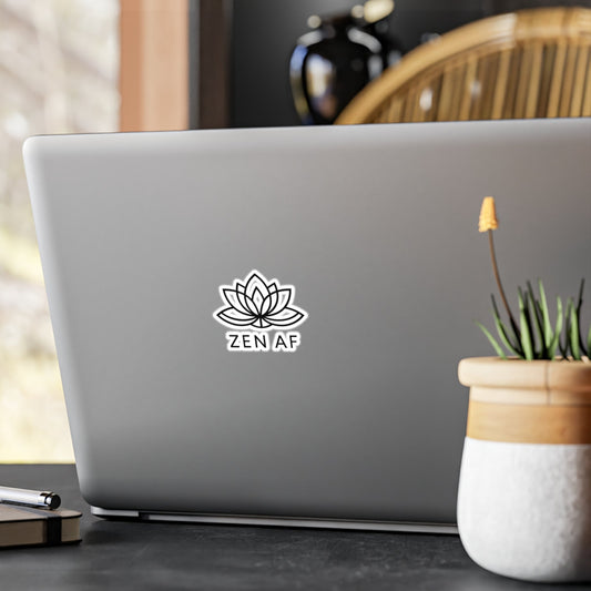 Laptop with a 'Zen AF' sticker on a desk with a plant and pen.