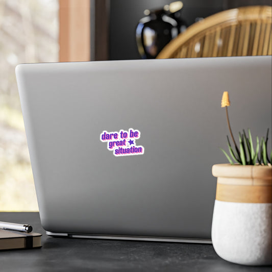 Laptop with a sticker on a desk with a plant and pen in the background