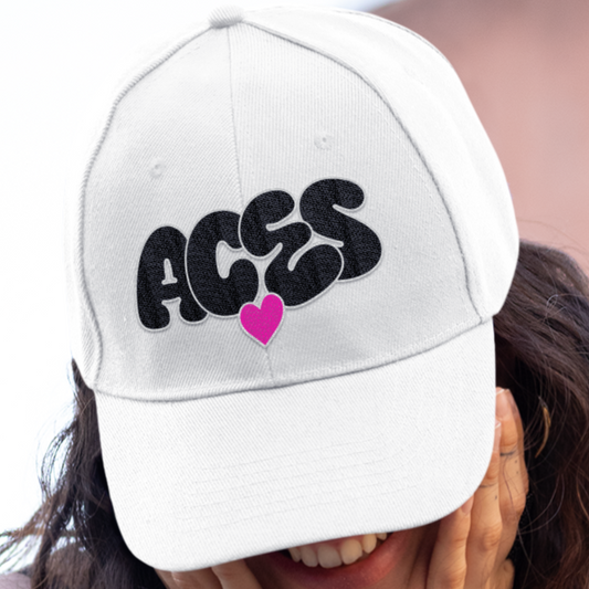 Person wearing a white cap with 'ACES' and a heart design, covering their face.