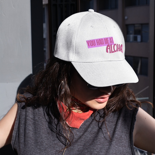 Person wearing a white cap with pink text and a gray sleeveless shirt.