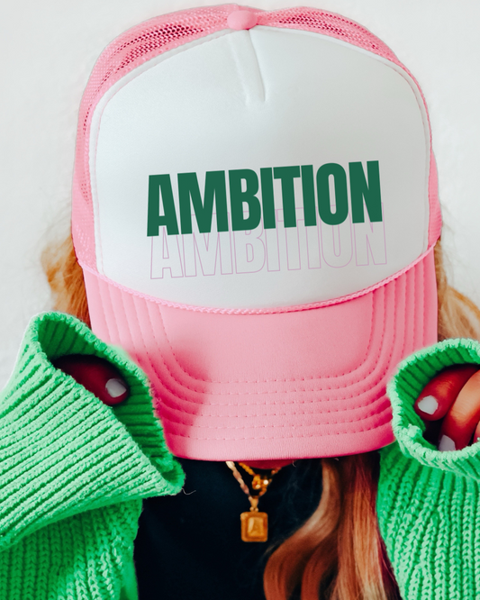 Pink cap with 'AMBITION' text, green gloves, and red shoes on a white background