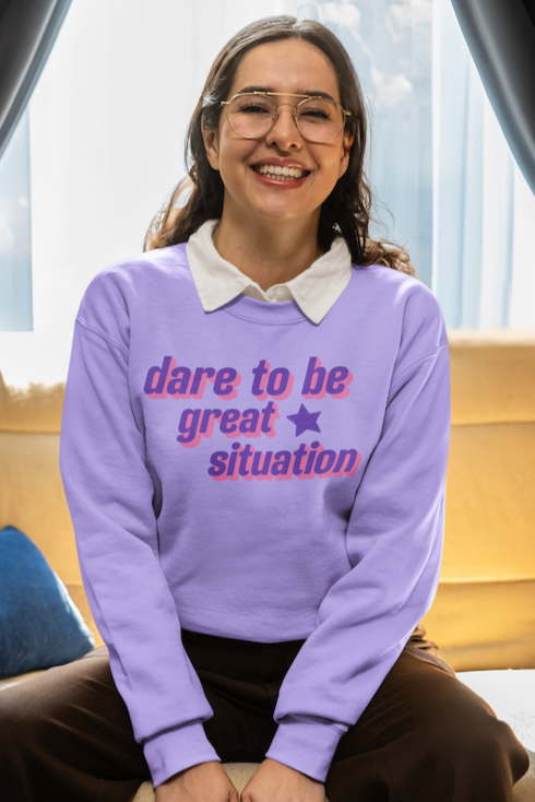 Person wearing a purple sweater with text, sitting on a couch.